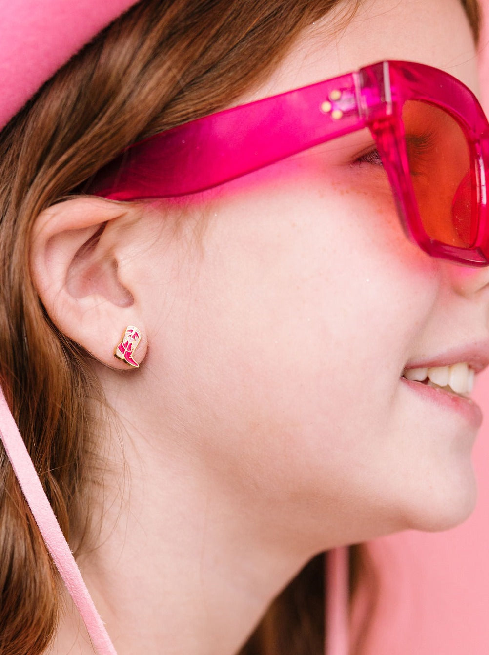 Cowboy boot stud earring worn on an ear, close-up