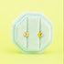Gold crescent moon cz studs on a teal jewelry box against a light neon green background