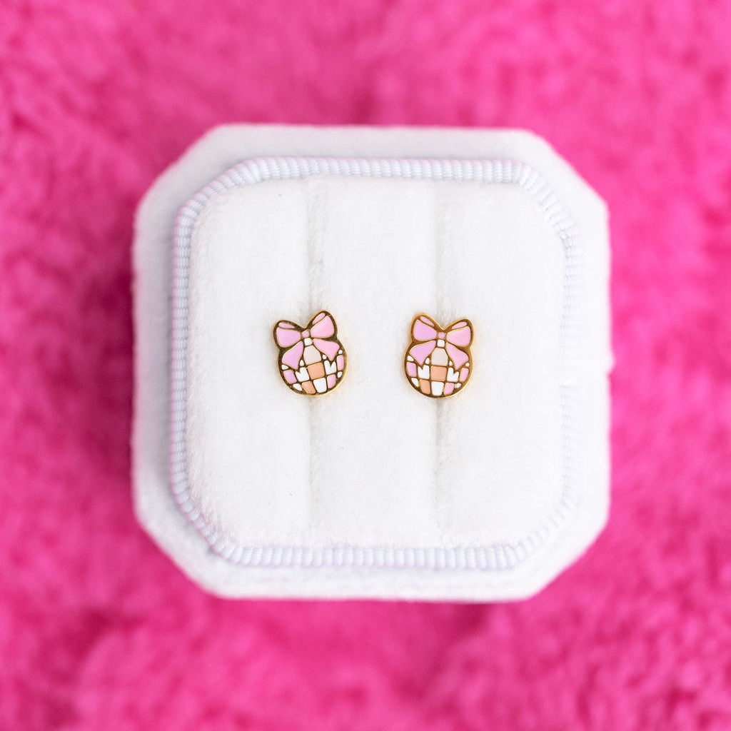 Disco balls with pink bows studs on a white jewelry box against a hot pink background