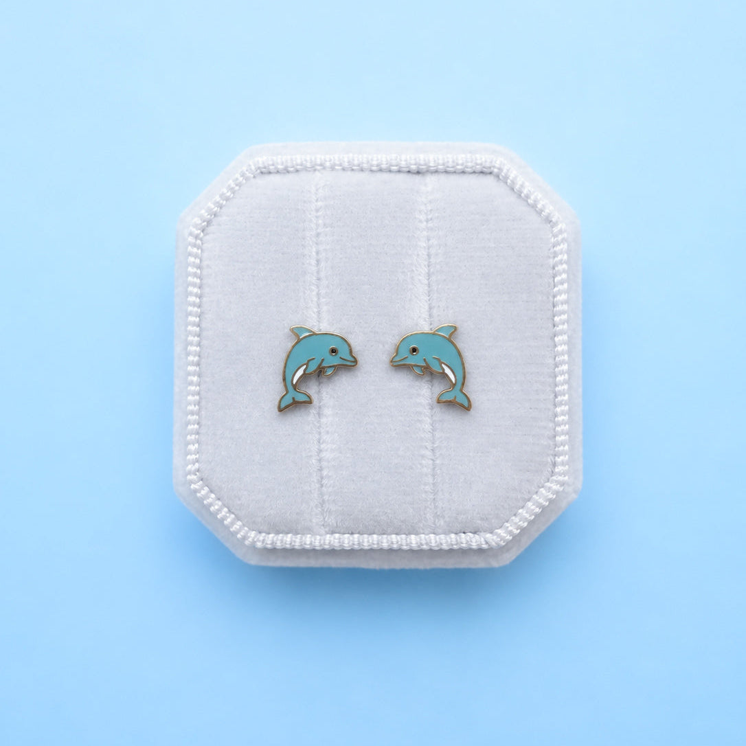 Dolphin earrings in a white box on a light blue background