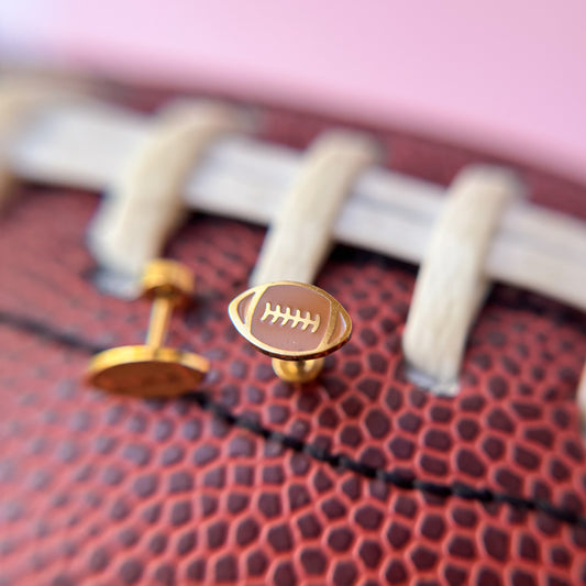 Close-up of a football with gold football studs on a blurred background