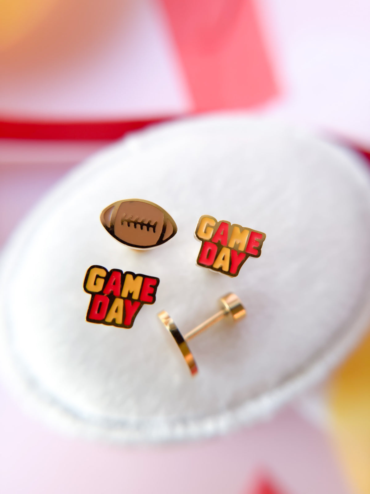 Pair of earrings with football and 'Game Day' design on a white surface.