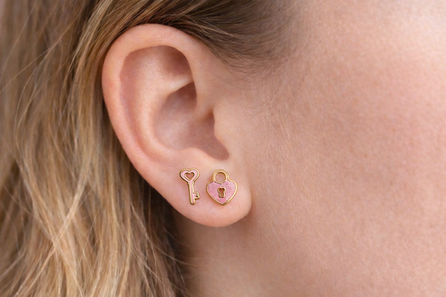 Pink heart lock and key earring set on girls ear lobe