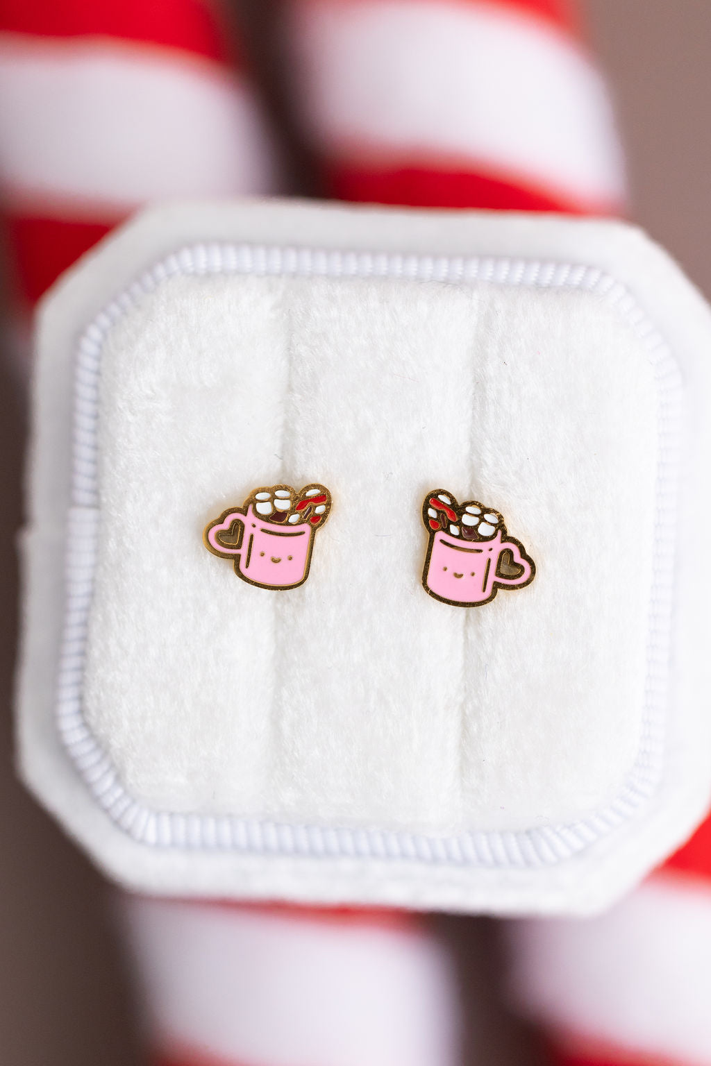 Hot Cocoa Stud Earrings on a white jewelry box against a candy cane background