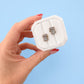 Hand holding a white jewelry box with koala studs on a blue background