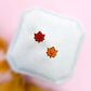 Small white box with red and orange maple leaf designs on a pink background