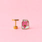 Two milk carton shaped stud earrings. One chocolate, one strawberry on a light pink background