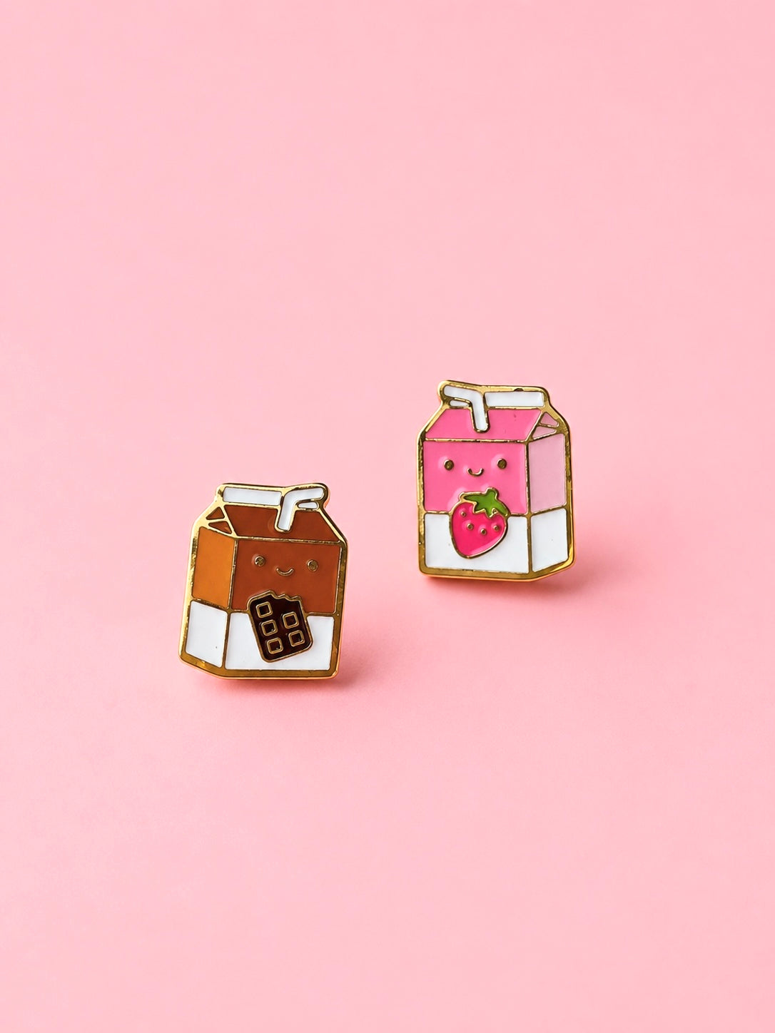 Two milk carton shaped stud earrings. One chocolate, one strawberry on a light pink background