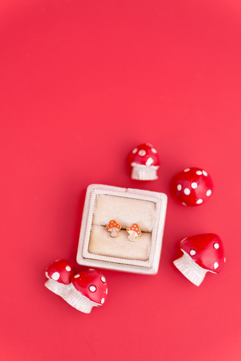 Red mushroom-shaped earrings with a white box on a red background