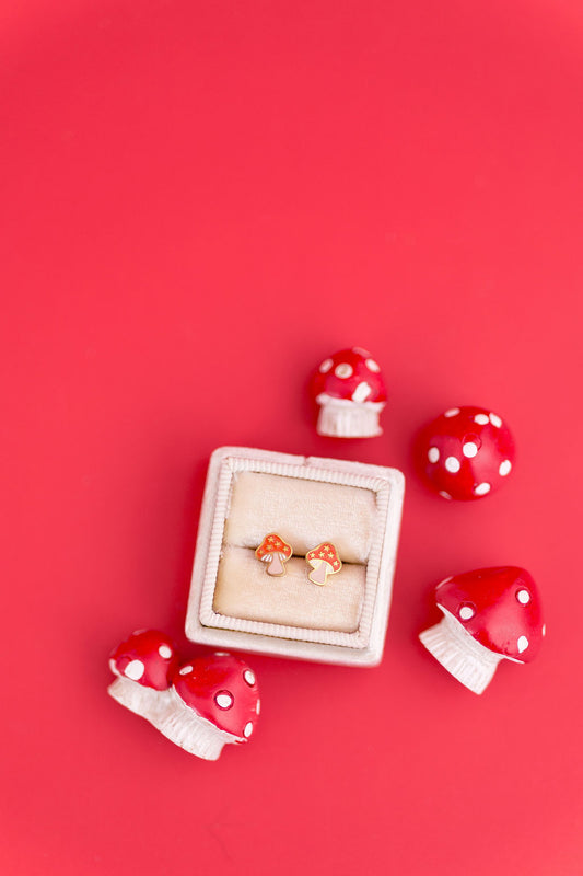 Red mushroom-shaped earrings with a white box on a red background