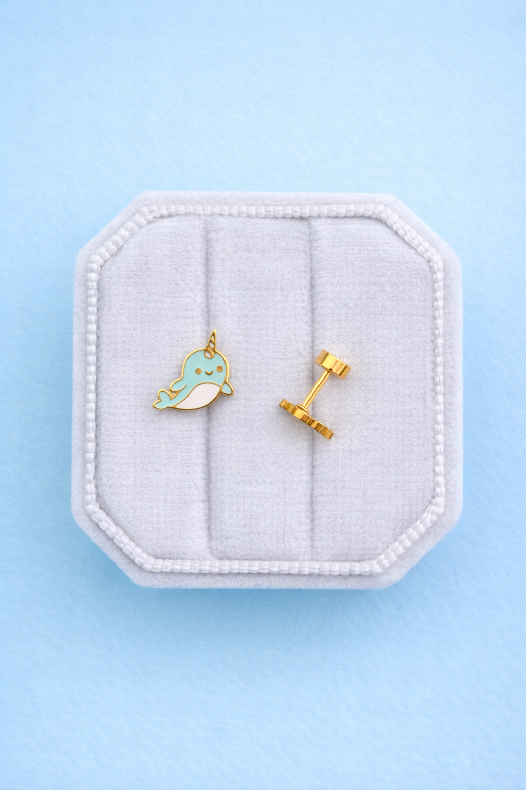 Narwhal studs with flat backs on a white jewelry box on a light blue background