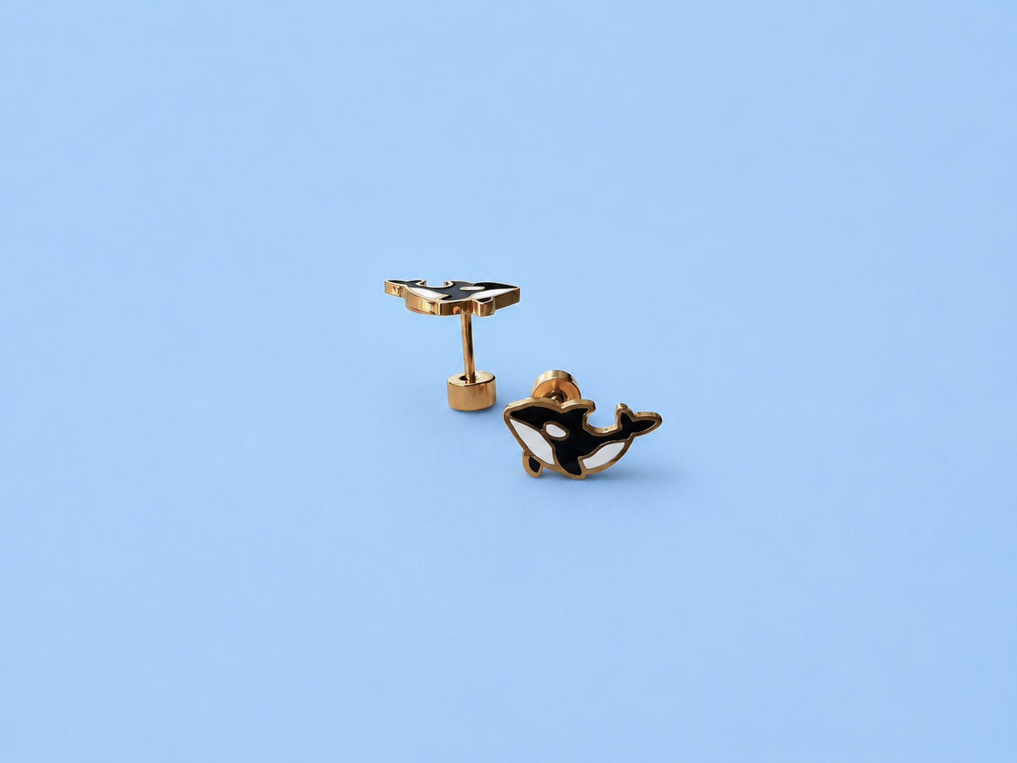 Black and gold whale-shaped earrings on a light blue background