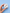 Hand holding a white jewelry box with orca whale earrings on a light blue background
