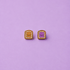 Peanut butter and jelly shaped enamel stud earrings on a light purple background