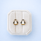 Penguin earrings on a textured white stand against a light blue background