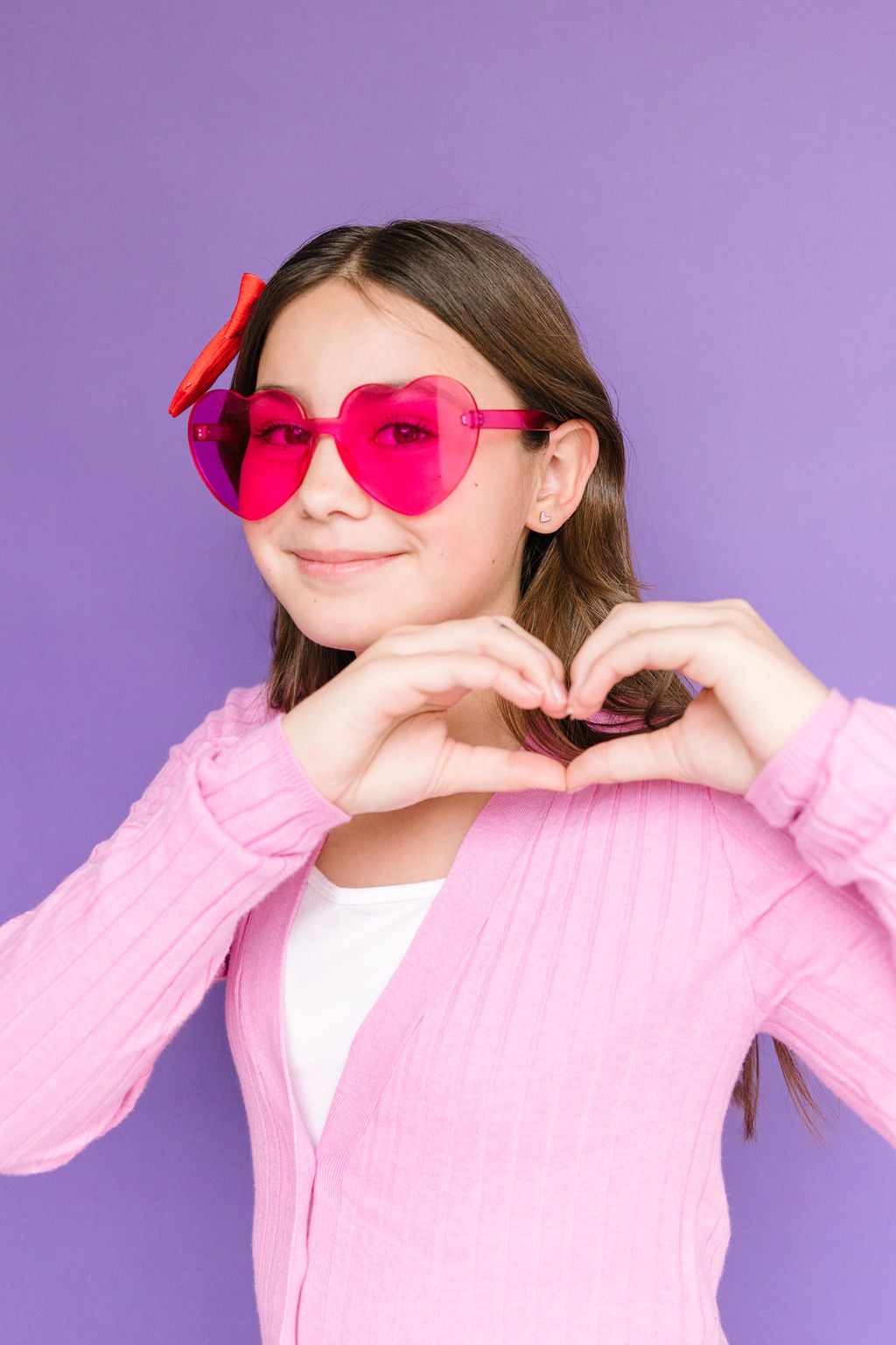 Pink heart stud earring worn on an ear