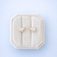Gold bear-shaped earrings in a decorative box on a light blue background