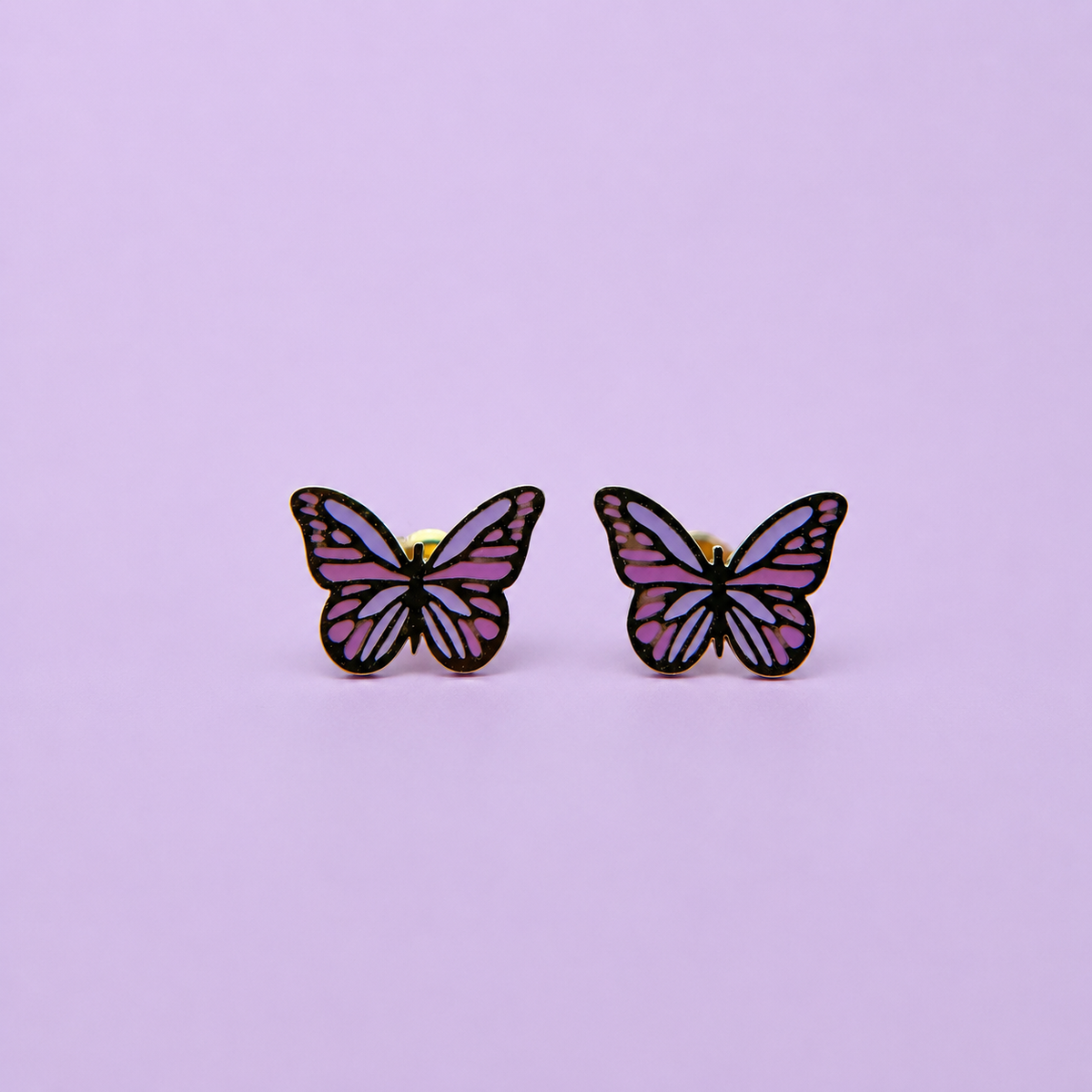 Pair of purple enamel butterfly earrings on a light purple background