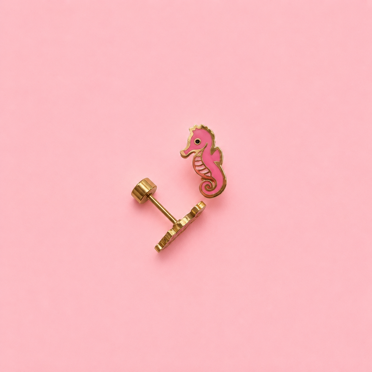 Pink seahorse earring on a pink background