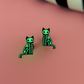 Glow in the dark green skeleton cat earrings on a pink background