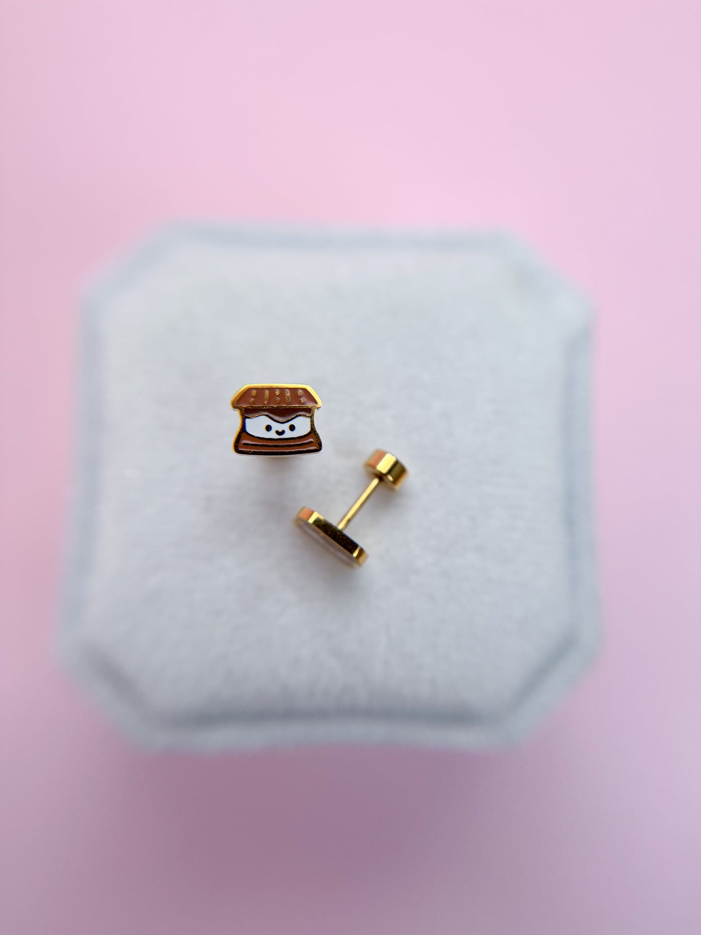 Kawaii s'mored shaped earring on a white cushion with a pink background