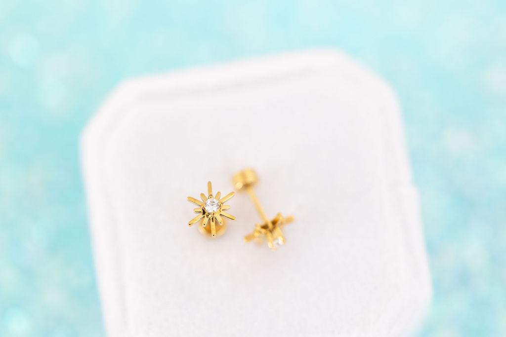 Starburst CZ Stud Earrings with flat backs on a white jewelry box on a teal background