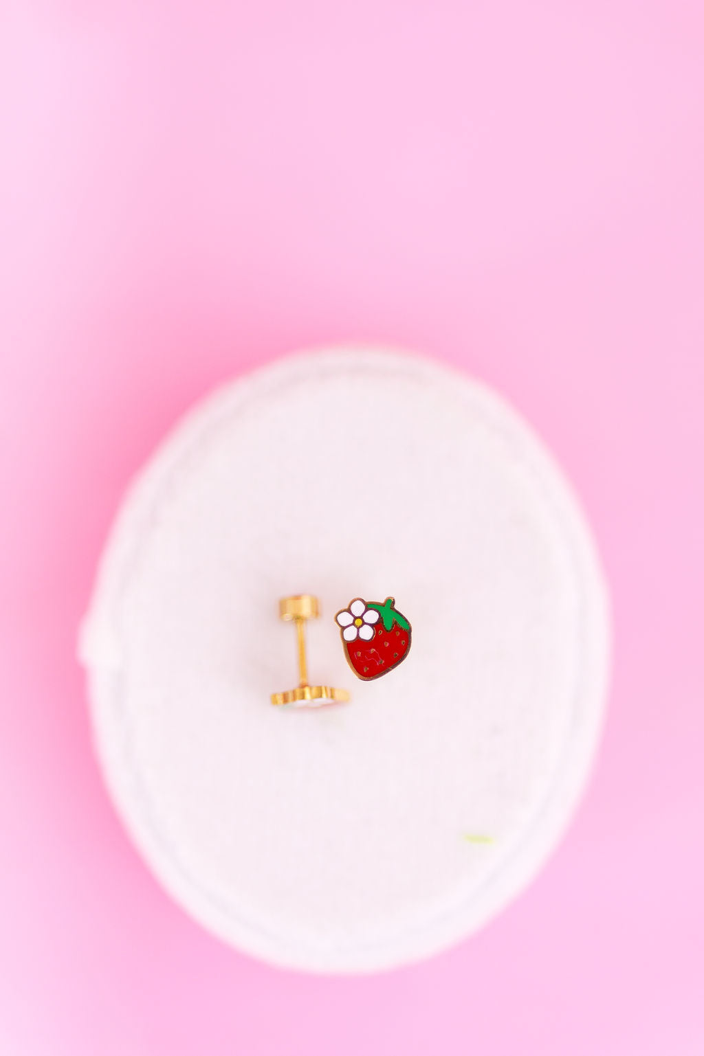 Strawberry blossom studs with flat backs on a white jewerly box on a light pink background