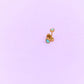 Gold earring with turquoise gemstones on a light purple background