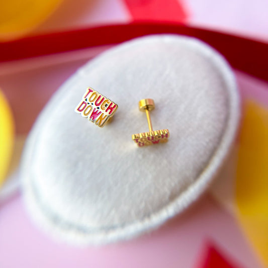 Gold earrings with 'Touchdown' text on a white background