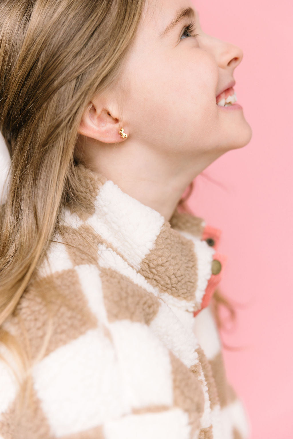 Gold unicorn stud earring worn on an ear