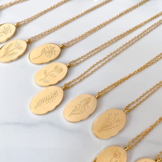 Close up of details of several gold plated birth month flower pendant necklaces
